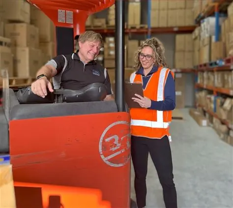 A consultant walking through a warehouse with a worker